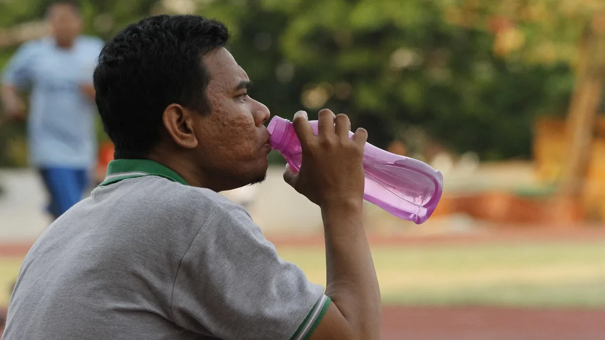 Deportista bebiendo agua durante un entrenamiento al aire libre