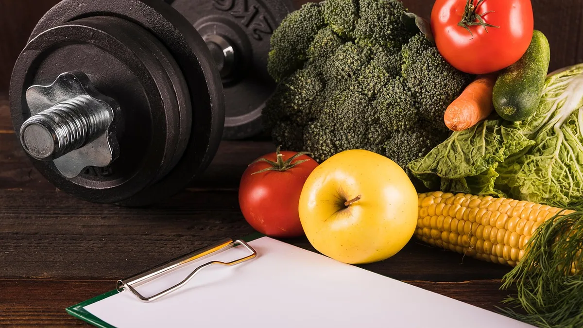 Mancuerna y verduras para representar pérdida de grasa y mantenimiento muscular